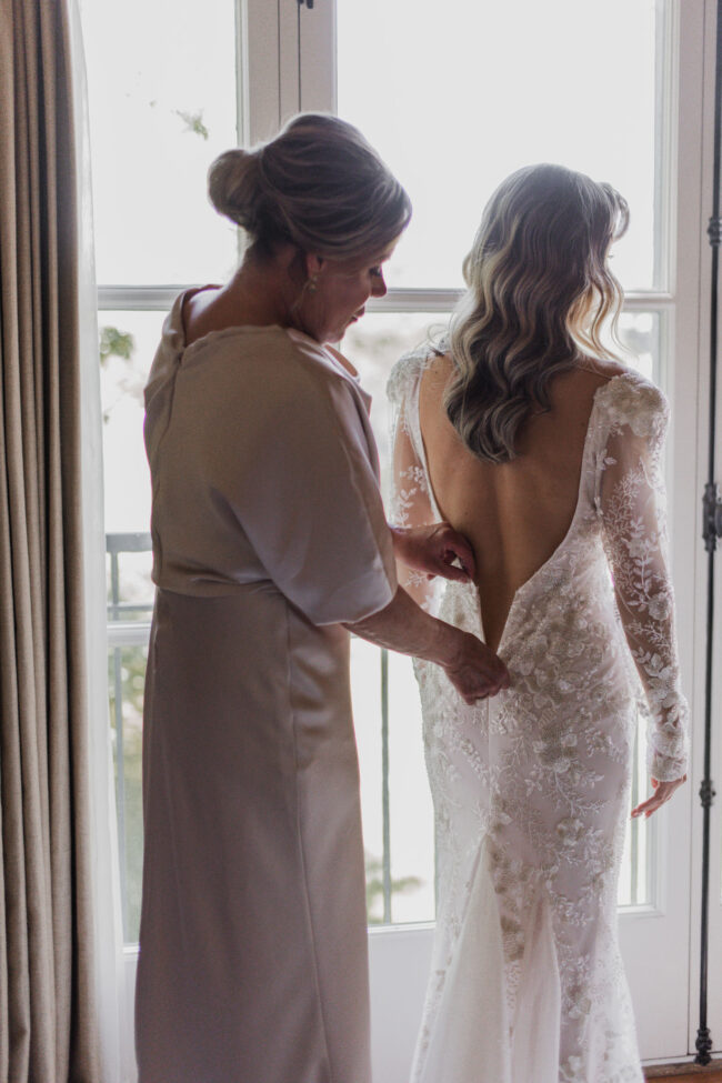 mother of the bride zipping up bride's dress