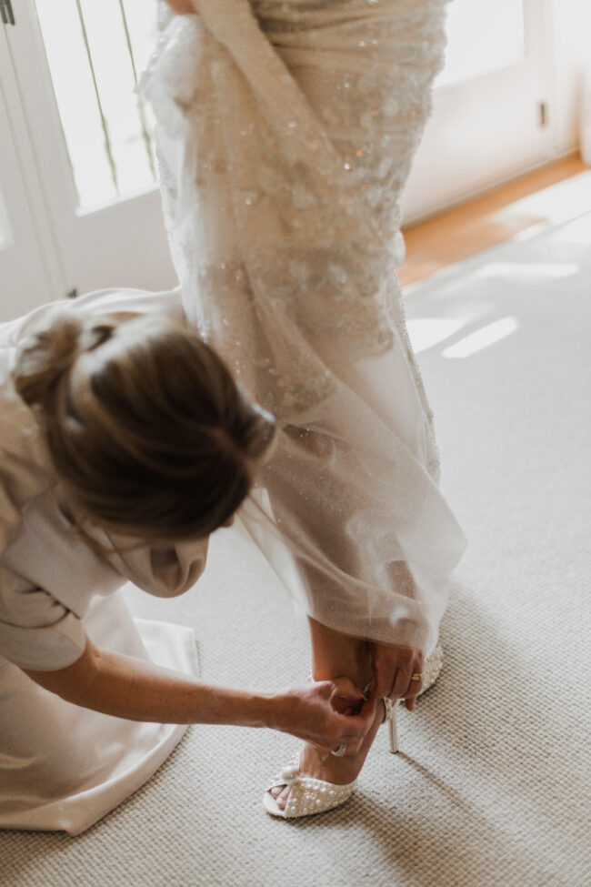 mother of the bride helping bride into shoes