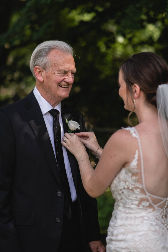 bride putting dad's boutonniere on