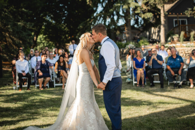 first kiss at wedding ceremony with guests in the background
