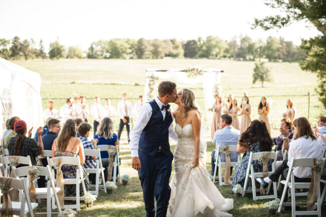 bride and groom kiss walking down aisle