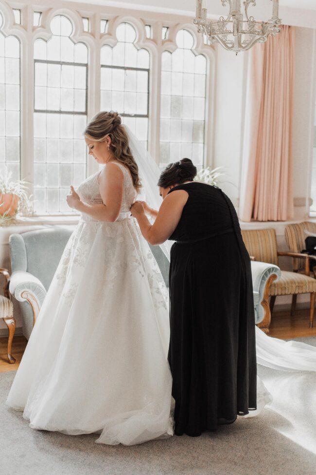 sister of the bride helping with dress